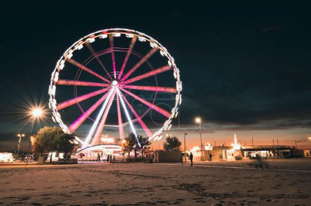 Photo for A long exposure shot of a Ferris wheel at night with colorful lights in Rimini, Italy - Royalty Free Image