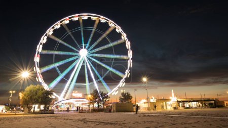 Téléchargez les photos : Un long plan d'exposition d'une grande roue la nuit avec des lumières colorées à Rimini, Italie - en image libre de droit