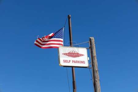 Téléchargez les photos : Un plan à angle bas du drapeau national américain et un panneau d'affichage de stationnement contre un ciel bleu - en image libre de droit