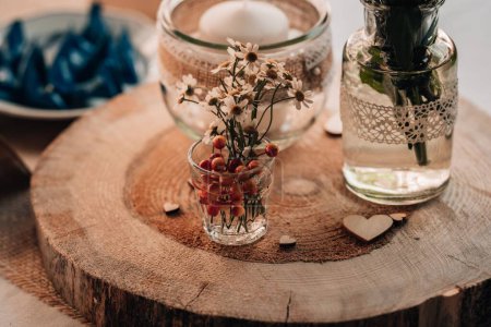 Foto de Un primer plano de una vela y un jarrón con flores en un tocón decorativo del árbol sobre una mesa - Imagen libre de derechos