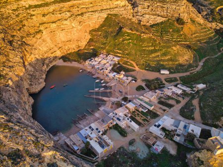Téléchargez les photos : Vue aérienne du coucher du soleil de Dwejra, une lagune d'eau de mer sur l'île de Gozo. Petit village de pêcheurs et tunnel maritime Exemple de mer intérieure à Malte. - en image libre de droit