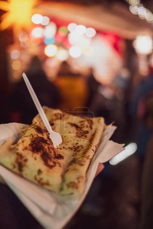 Téléchargez les photos : Une main humaine tenant de délicieux aliments dans le marché de Noël - en image libre de droit