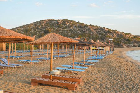Téléchargez les photos : La plage de sable avec chaises longues et parasols au toit de chaume. - en image libre de droit