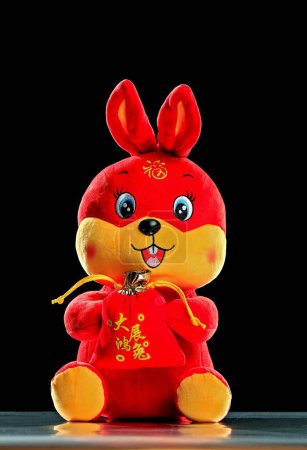 Téléchargez les photos : Un plan vertical d'un lapin en peluche rouge du Nouvel An chinois sur un fond noir - en image libre de droit