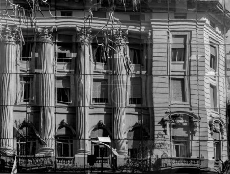 Téléchargez les photos : Un vieux bâtiment avec des colonnes réfléchissant sur des fenêtres en miroir tourné en niveaux de gris - en image libre de droit