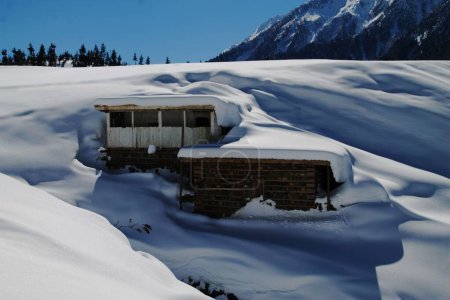 Téléchargez les photos : La vue des bâtiments couverts de neige par une journée ensoleillée à flanc de montagne - en image libre de droit