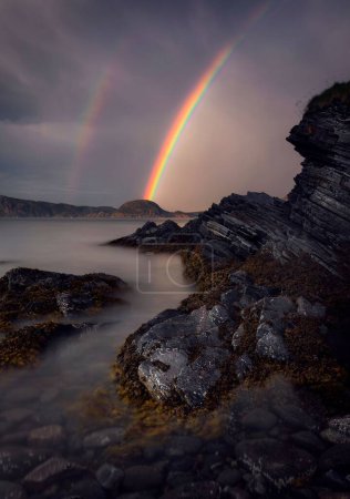 Foto de Un disparo vertical de arco iris doble en el cielo sobre una costa rocosa en skjervoy, Noruega - Imagen libre de derechos