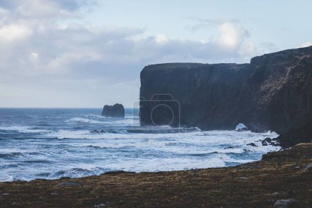 Téléchargez les photos : Les vagues de la mer et une falaise côtière devant le ciel bleu avec des nuages - en image libre de droit