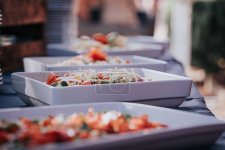 Téléchargez les photos : Un focus sélectif de salades dans des bols blancs en rangée sur une table de banquet - en image libre de droit