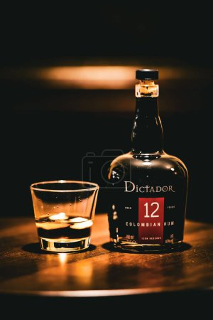 Photo for A closeup of a Dictador Columbian rum on a wooden table with glass - Royalty Free Image