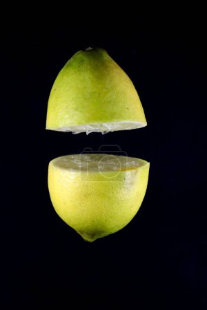 Téléchargez les photos : Un citron coupé isolé sur fond noir - en image libre de droit