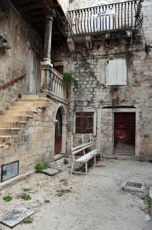 Téléchargez les photos : Un vieux coin paisible de Trogir, Croatie avec ruines de la ville avec un banc à l'extérieur - en image libre de droit
