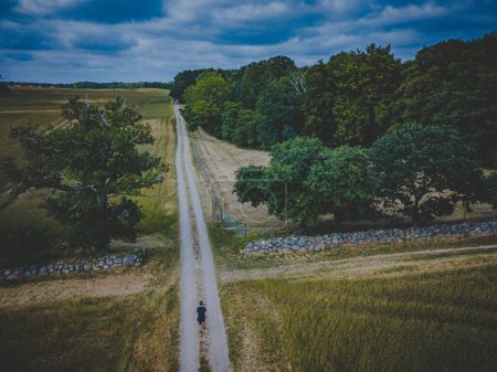 Téléchargez les photos : Vue aérienne d'un jeune homme marchant le long d'un sentier dans la belle campagne du sud de la Zélande - en image libre de droit