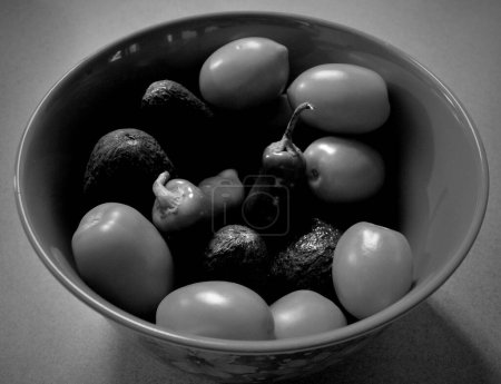Foto de Un tiro blanco y negro de aceitunas de pimientos pequeños y aguacates pequeños en un tazón - Imagen libre de derechos