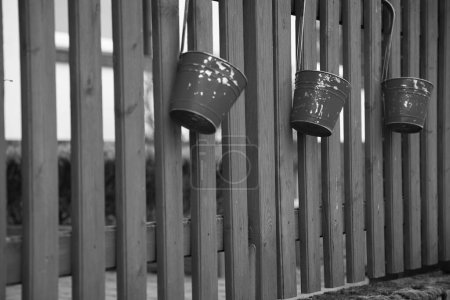 Foto de Una escala de grises de cubos colgando de una cerca de madera - Imagen libre de derechos