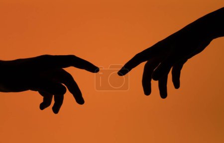 Foto de Una silueta de dos manos que se alcanzan entre sí, aisladas sobre un fondo naranja - Imagen libre de derechos