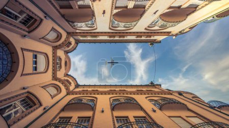Photo for A low angle shot of the airplane flying over the building - Royalty Free Image