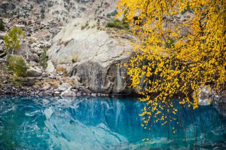 Foto de Un lago azul claro con hojas de árbol amarillo y el reflejo de las montañas - Imagen libre de derechos