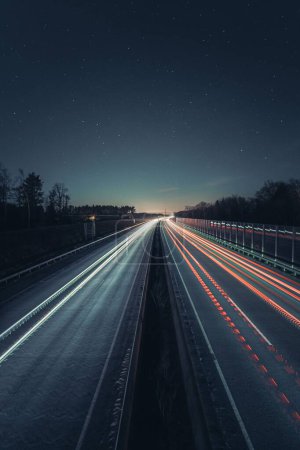 Téléchargez les photos : Un coup vertical des feux de voiture sur les routes avec un long effet d'exposition pendant la nuit - en image libre de droit