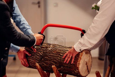 Photo for A closeup shot of people sawing a wooden log in a room, in suits, the concept of tradition and customs - Royalty Free Image