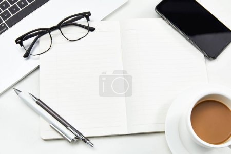 Téléchargez les photos : Une tasse de café blanc sur un bureau avec divers appareils de bureau - en image libre de droit