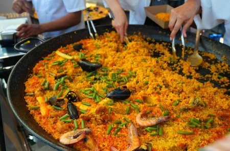 Téléchargez les photos : Plan rapproché de personnes qui cuisinent de la paella dans un marché de rue - en image libre de droit