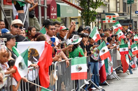 Téléchargez les photos : Un groupe de personnes avec des drapeaux dans une ambiance festive pendant le défilé de la fête de l'indépendance du Mexique - en image libre de droit