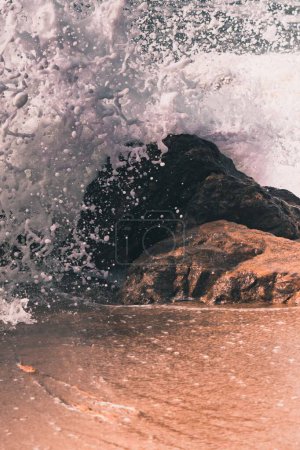 Foto de Un disparo vertical de las olas salpicantes del mar en la costa rocosa - Imagen libre de derechos