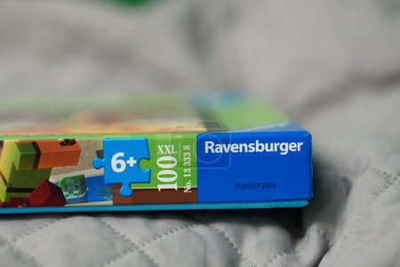 Téléchargez les photos : Un gros plan de puzzle Minecraft de marque "Ravensburger" en boîte sur lit avec fond flou - en image libre de droit