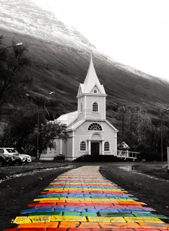 Téléchargez les photos : Un plan vertical en niveaux de gris de la rue Rainbow Walkway avec église blanche à Seyoisfjorour, Islande - en image libre de droit
