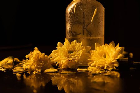 Téléchargez les photos : Une bouteille du parfum Calvin Klein Cologne For Men aux fleurs jaunes sur fond noir - en image libre de droit