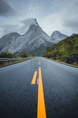 Photo for A vertical shot of a road surrounded by rocky hills under a cloudy sky in winter - Royalty Free Image