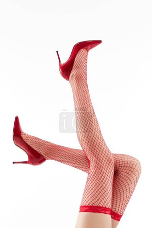 Photo for A woman with beautiful legs wearing red heels and stockings on a white background - Royalty Free Image