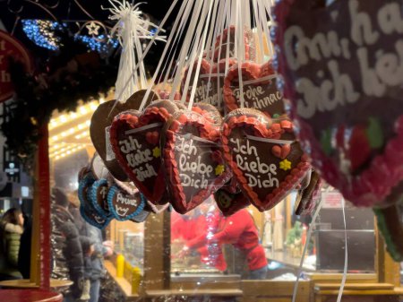 Téléchargez les photos : Marché de Noël le soir en ville. Coeurs de pain d'épice avec le texte allemand : Je t'aime. En arrière-plan est l'éclairage public bleu. - en image libre de droit