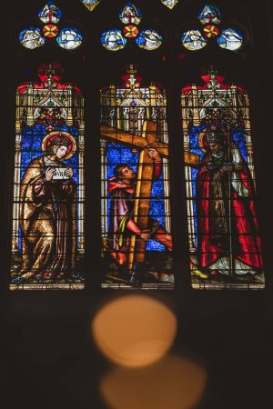 Photo for A vertical shot of big Stained glass with saints at a local church on the dark background - Royalty Free Image