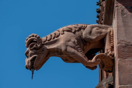 Foto de Un primer plano de una escultura de piedra de la catedral Freiburger Munster contra un cielo azul. - Imagen libre de derechos