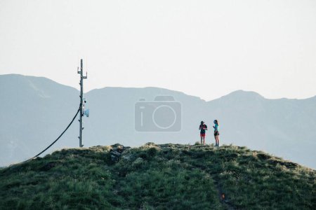 Téléchargez les photos : Un jeune homme et une jeune femme debout ensemble au sommet d'une colline près d'une tour de téléphonie mobile - en image libre de droit