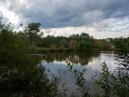 Téléchargez les photos : Un beau plan d'un lac entouré d'arbres sous un ciel nuageux - en image libre de droit