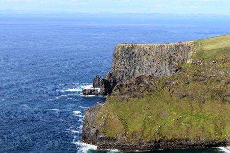 Photo for A mesmerizing view of the rocky cliff of Moher in county Clare in Ireland, covered by grass, and a breathtaking view of a seascape on a sunny day - Royalty Free Image