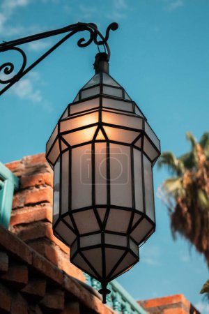 Téléchargez les photos : Plan vertical d'un lampadaire aux motifs noirs attaché à un cintre métallique sous le ciel bleu - en image libre de droit