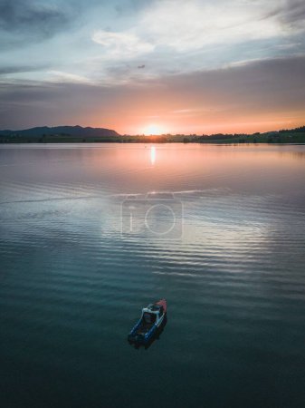 Téléchargez les photos : Un drone plan vertical d'un bateau dans un lac avec ciel nuageux au coucher du soleil - en image libre de droit