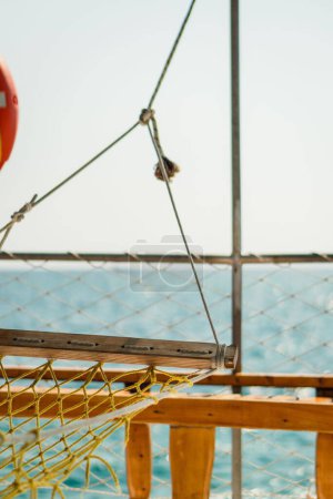 Foto de Un tiro vertical selectivo del foco de un barco de una hamaca de red amarilla con un mar azul en el fondo - Imagen libre de derechos