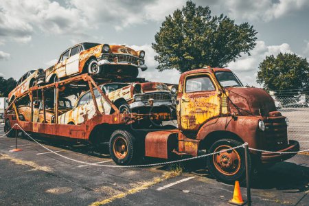 Photo for An old rusted truck hauler with rusted classic cars in Colonial Heights, USA - Royalty Free Image