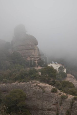 Téléchargez les photos : Vue verticale d'une maison sur une falaise par temps brumeux - en image libre de droit