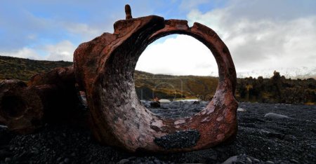 Foto de Un primer plano de una vieja tubería oxidada en el oscuro suelo rocoso. Snaefellsnes, Islandia. - Imagen libre de derechos
