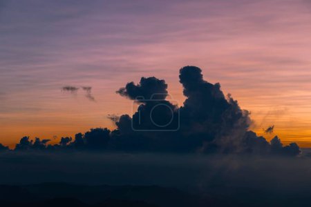 Foto de Nubes fascinantes forman siluetas con un cielo anaranjado brillante en el fondo durante la puesta del sol - Imagen libre de derechos