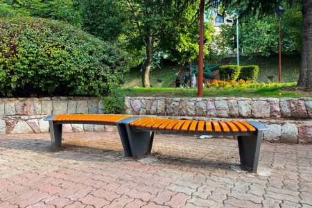 Photo for A modern wooden bench in a public park - Royalty Free Image