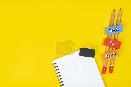 Téléchargez les photos : Un carnet, une gomme, des crayons et un bloc de bois avec le texte RETOUR À LA BASE sur fond jaune - en image libre de droit