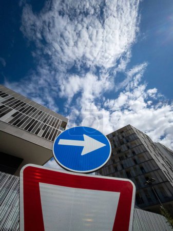 Photo for A blue right direction arrow on a road sign against modern buildings in an urban area - Royalty Free Image