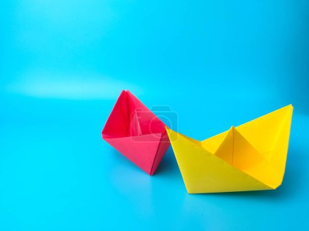Photo for A big red paper ship and smaller yellow one on turquoise background - leadership concept - Royalty Free Image